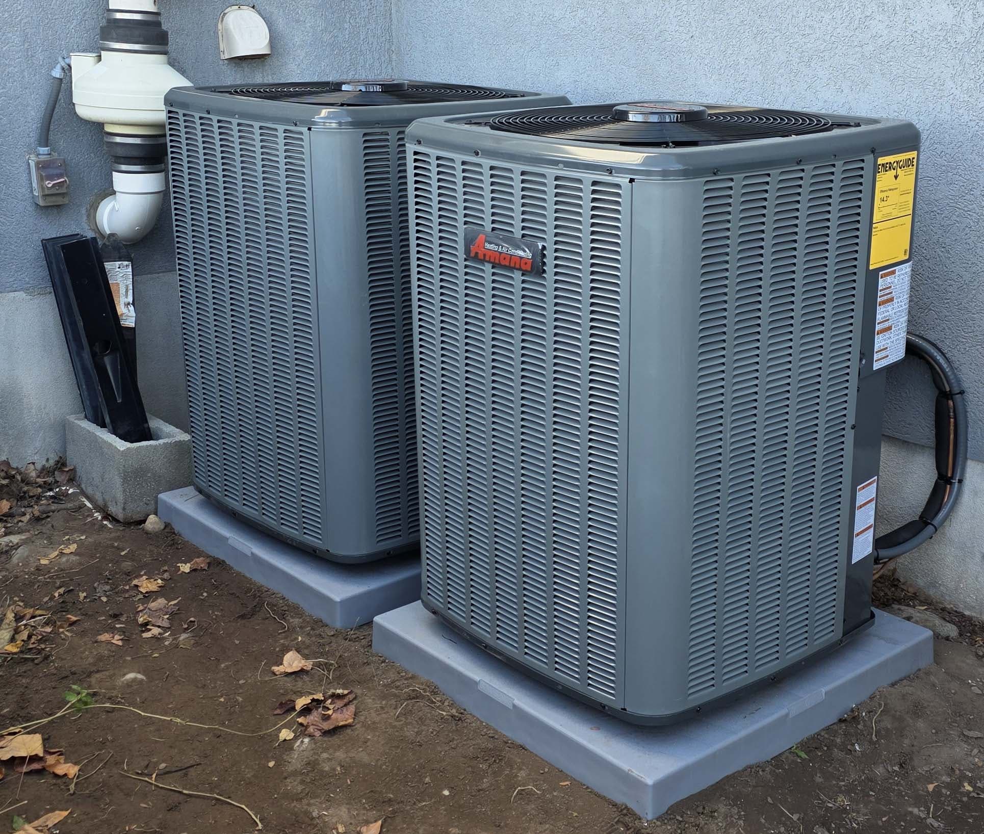 Two Amana outdoor AC condensers — Wasatch Peaks side-yard install on level pads