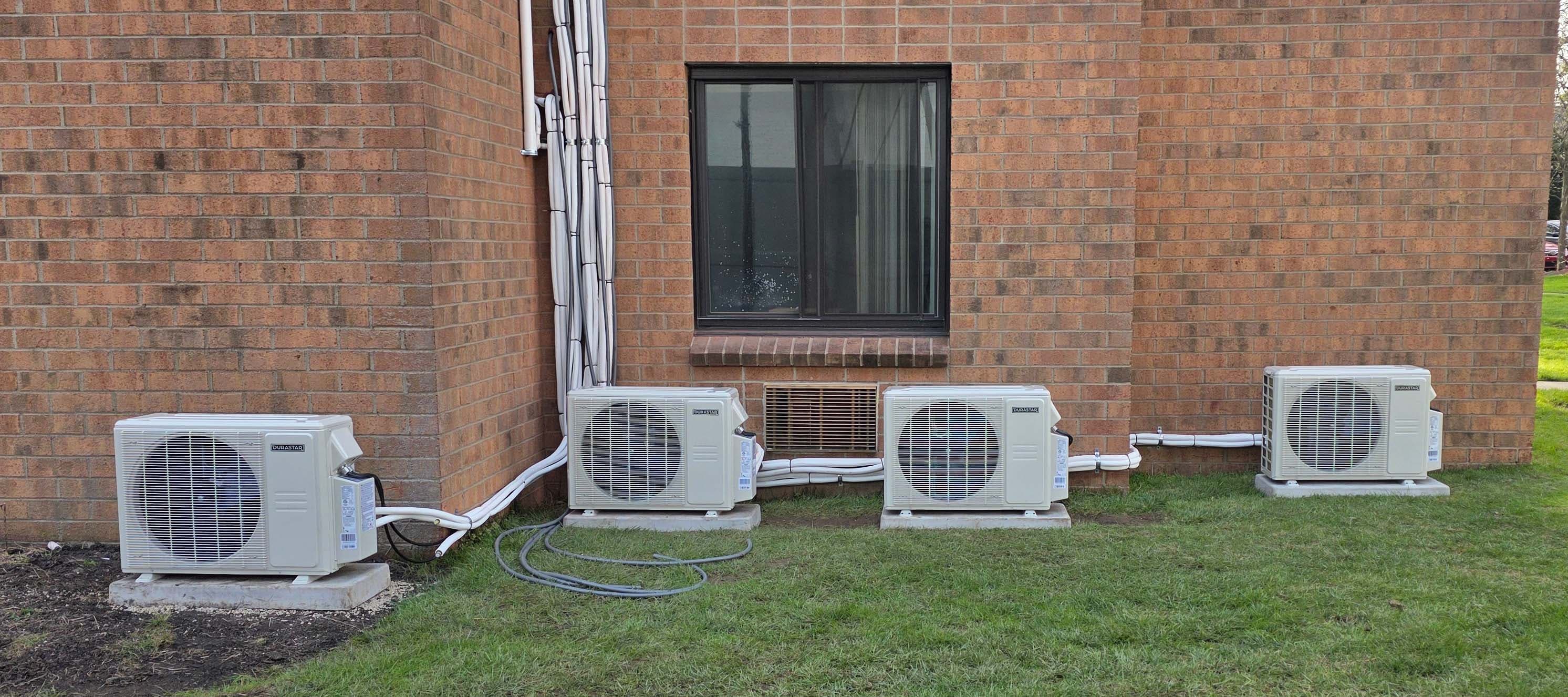 Multi-zone mini-split bank — four outdoor units along a brick exterior