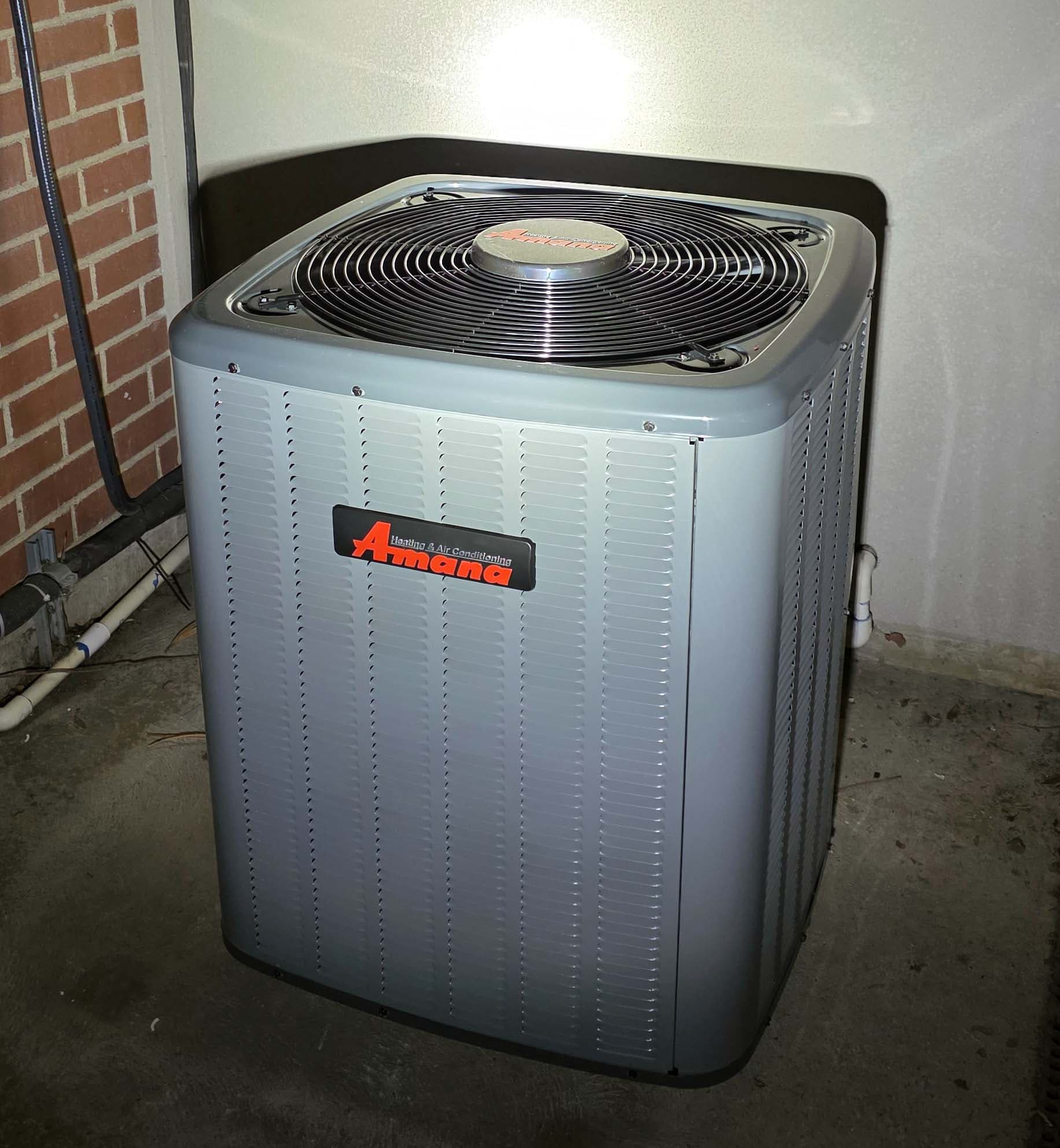 Close-up of Amana outdoor AC condenser at brick exterior